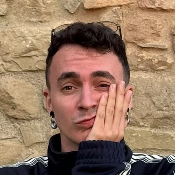 Arnau Palacín amb la mà a la galta, davant d’un mur de pedra